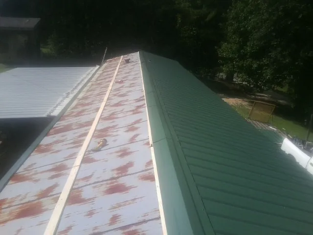 Old rusted panels beside newly installed green metal roofing — Wind Damage Roof Repair by Roofing Brothers in Parshall