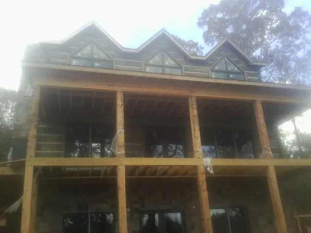 Dormers and porch framing on a large log home under construction — Roof Coating work by our crew in Parshall