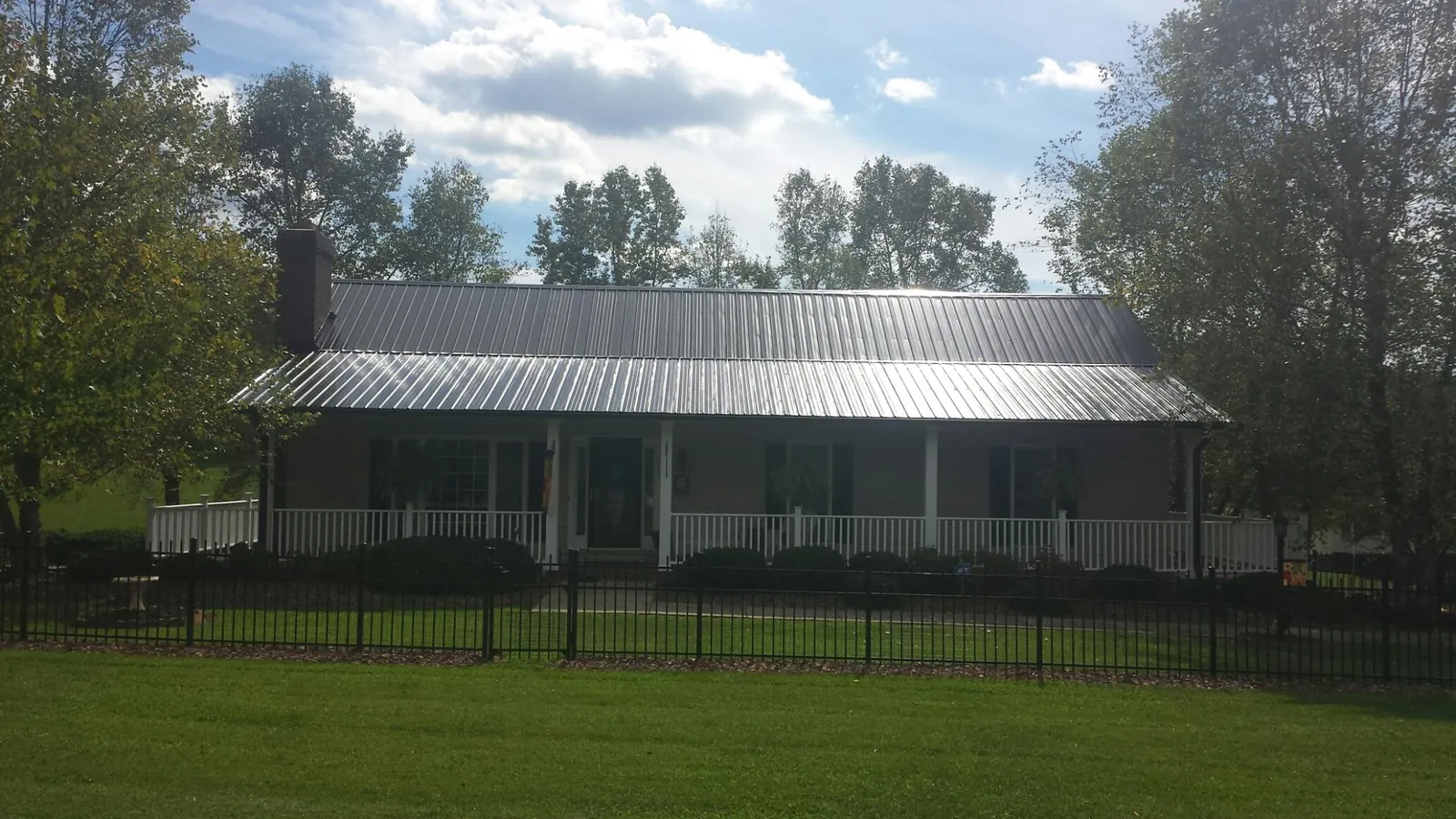 Gray metal roof on a brick ranch with a full width front porch — Gutter Guard Installation work by our crew in Parshall