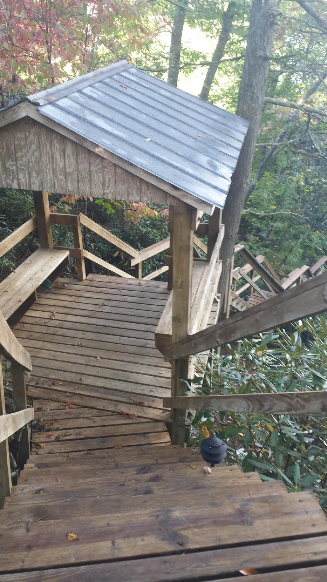 Metal roofed shelter over wooden steps on a wooded walkway — Skylight Repair & Installation work by our crew in Parshall