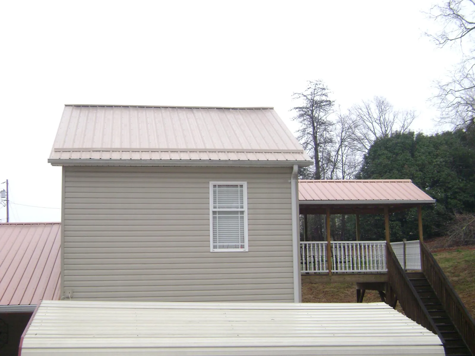 Tan metal roofs on a two story addition and attached porch, from a Roof Replacement job in Parshall